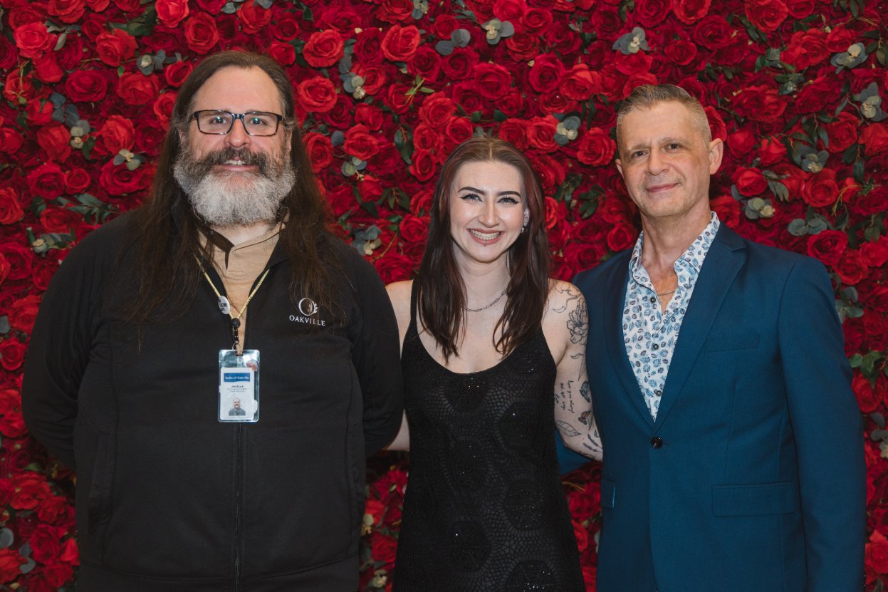 Three guests posing before a red rose flower wall