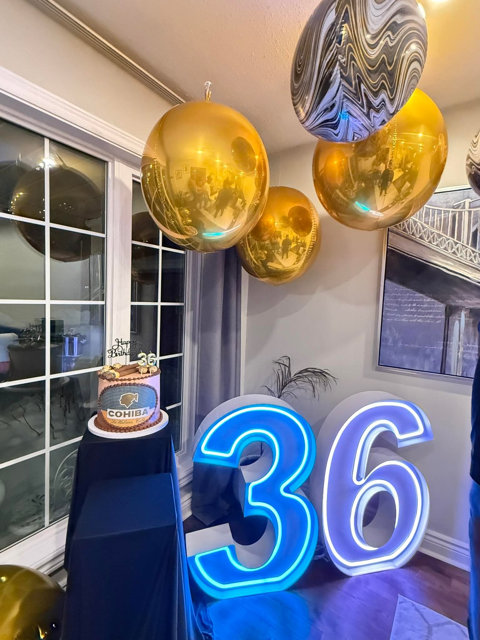 36th birthday setup with blue neon 36, gold balloons and a cake