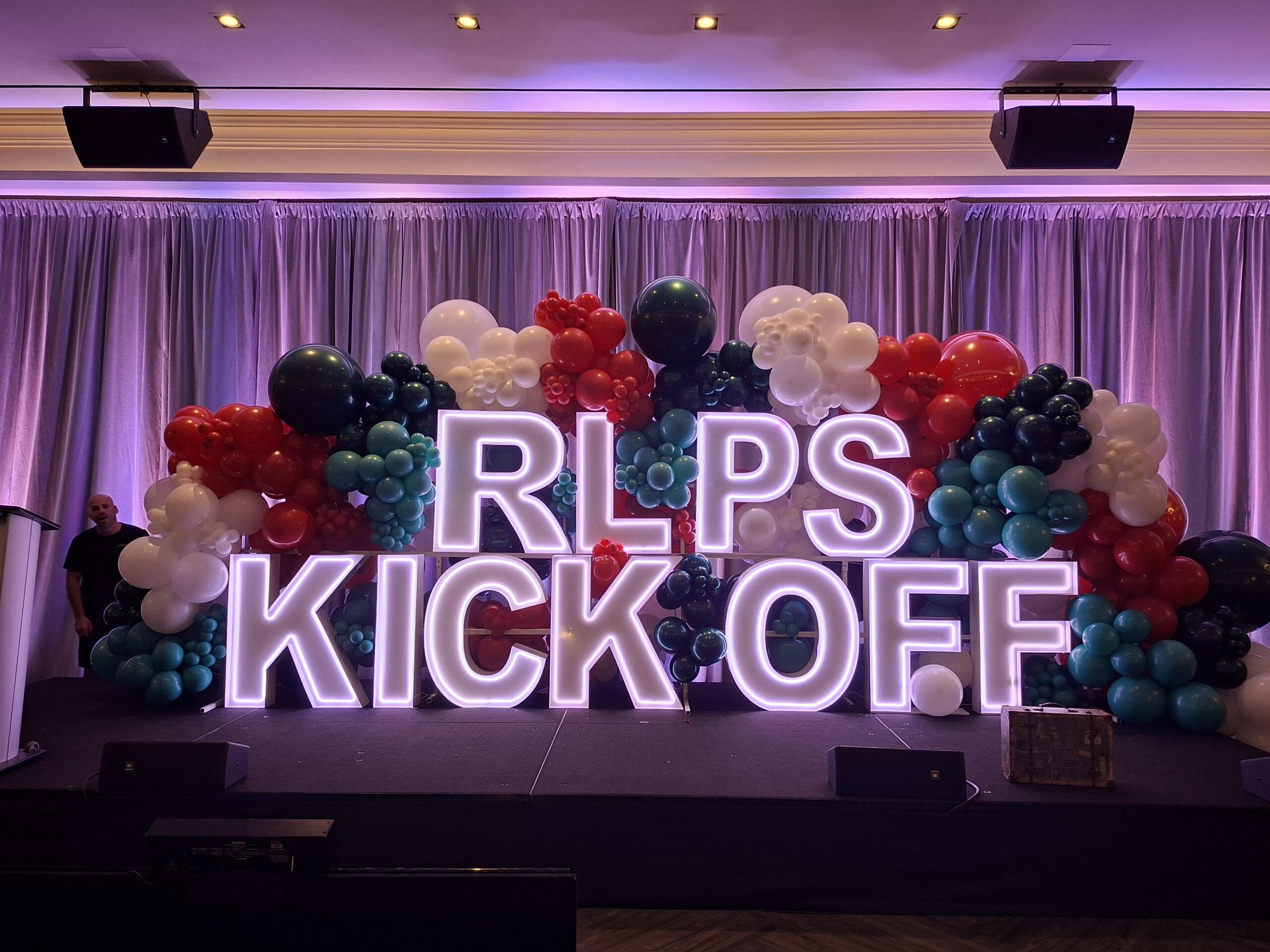 Stage with illuminated RLPS KICK OFF letters and balloon clusters