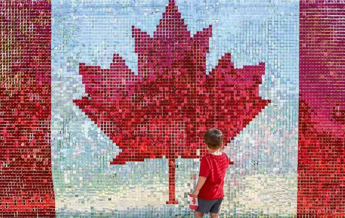 Small child touching a giant sequin Canadian flag wall
