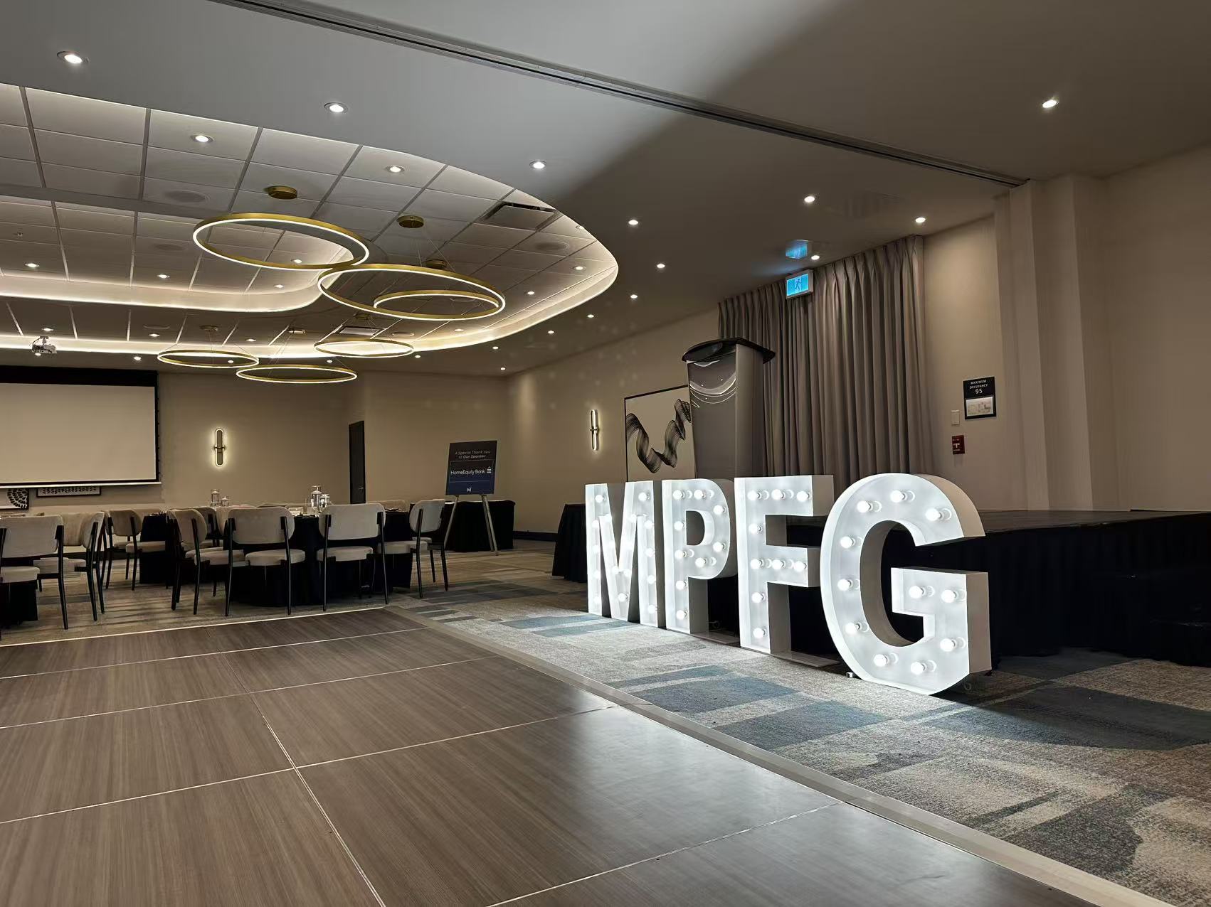 Illuminated marquee letters MPFG on a dance floor in a banquet hall