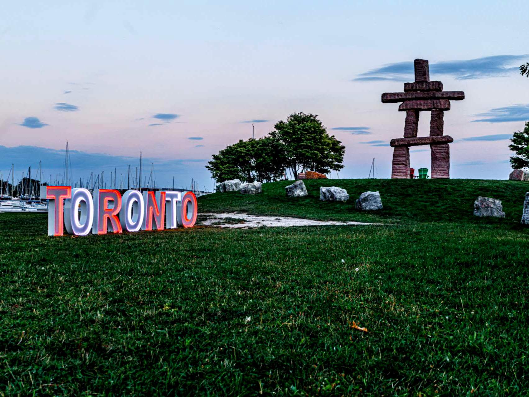 Illuminated TORONTO marquee letters glowing red and white on the waterfront at dusk
