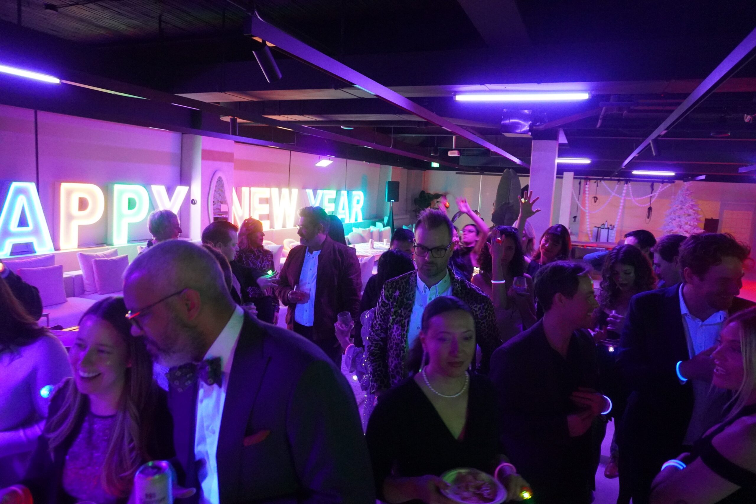 New Year's Eve party crowd with rainbow neon Happy New Year letters
