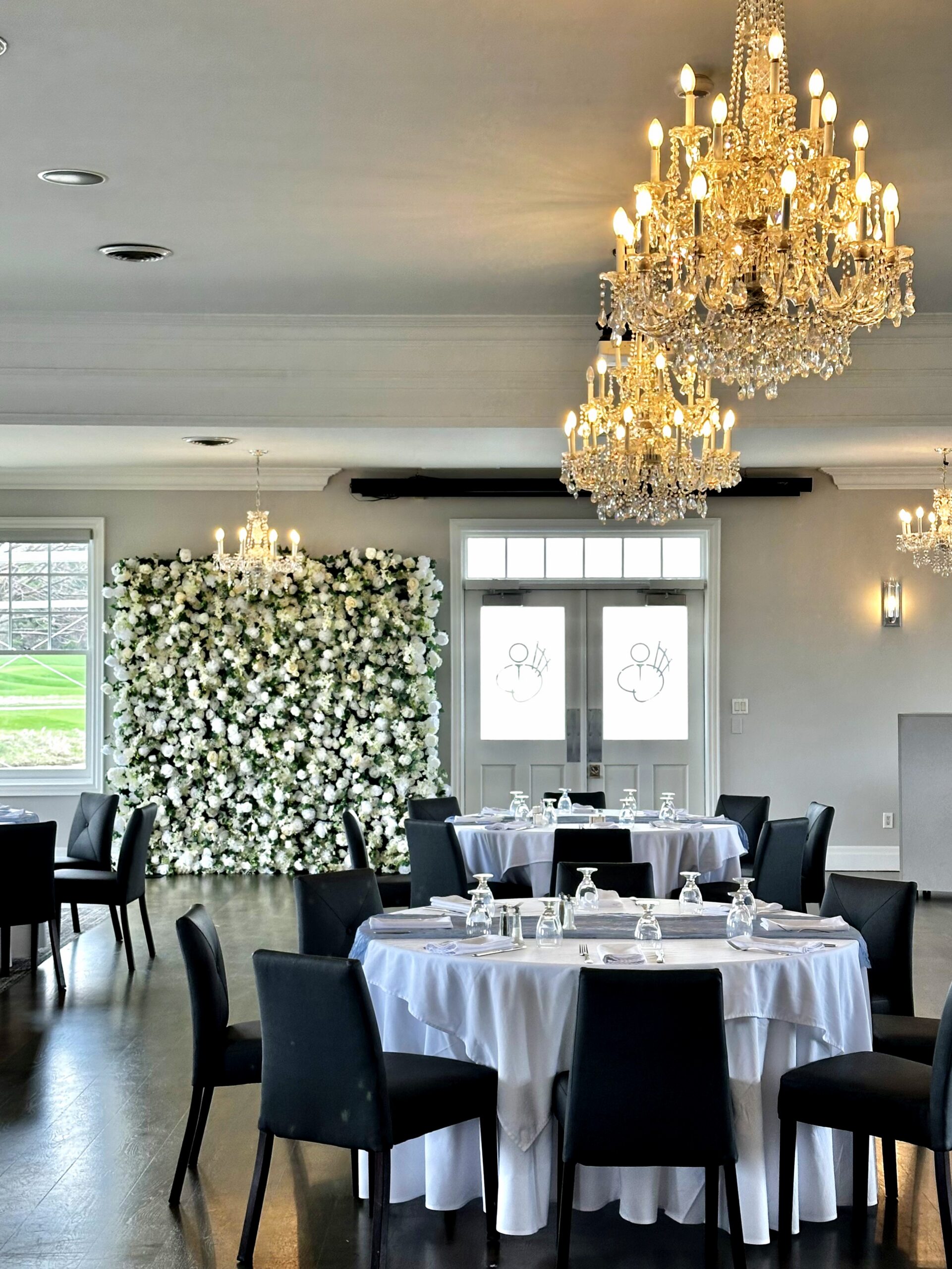 Elegant banquet hall with crystal chandeliers and a white flower wall