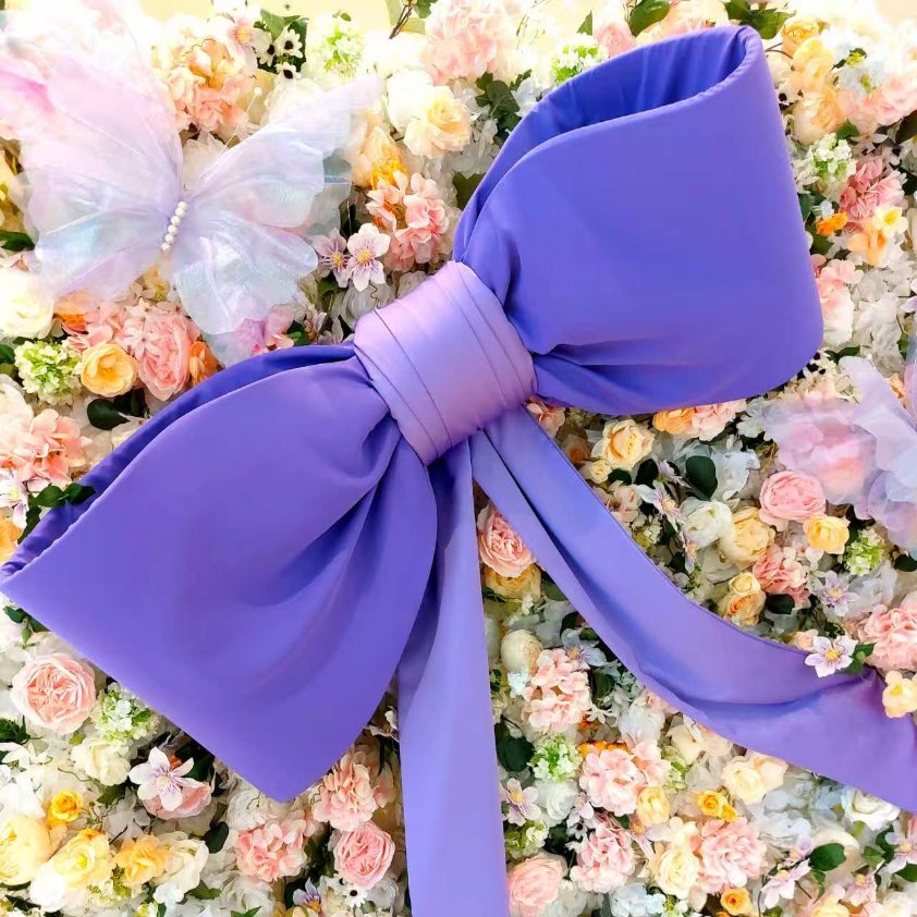 Giant purple satin bow on a pastel flower wall with a butterfly
