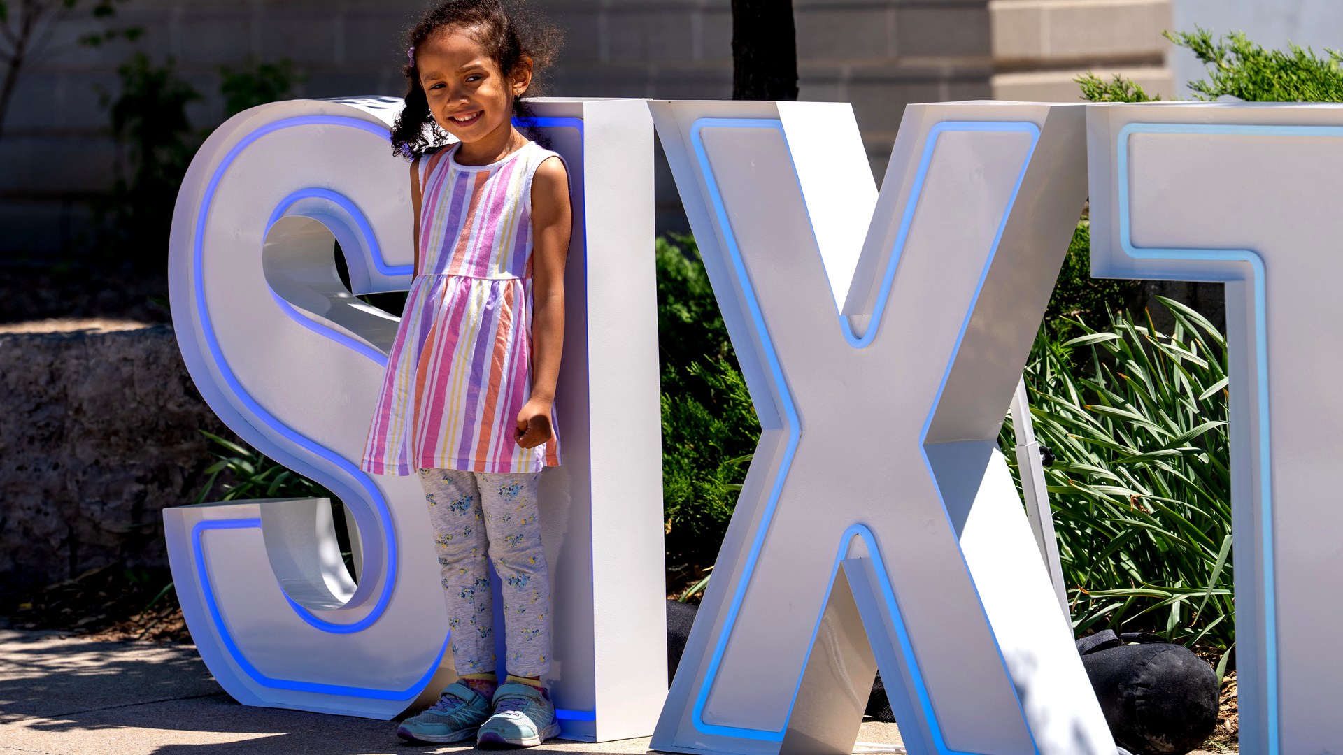 Young girl posing with SIXT marquee letters