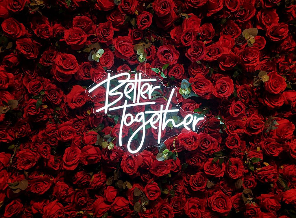 Better Together neon sign on red rose wall